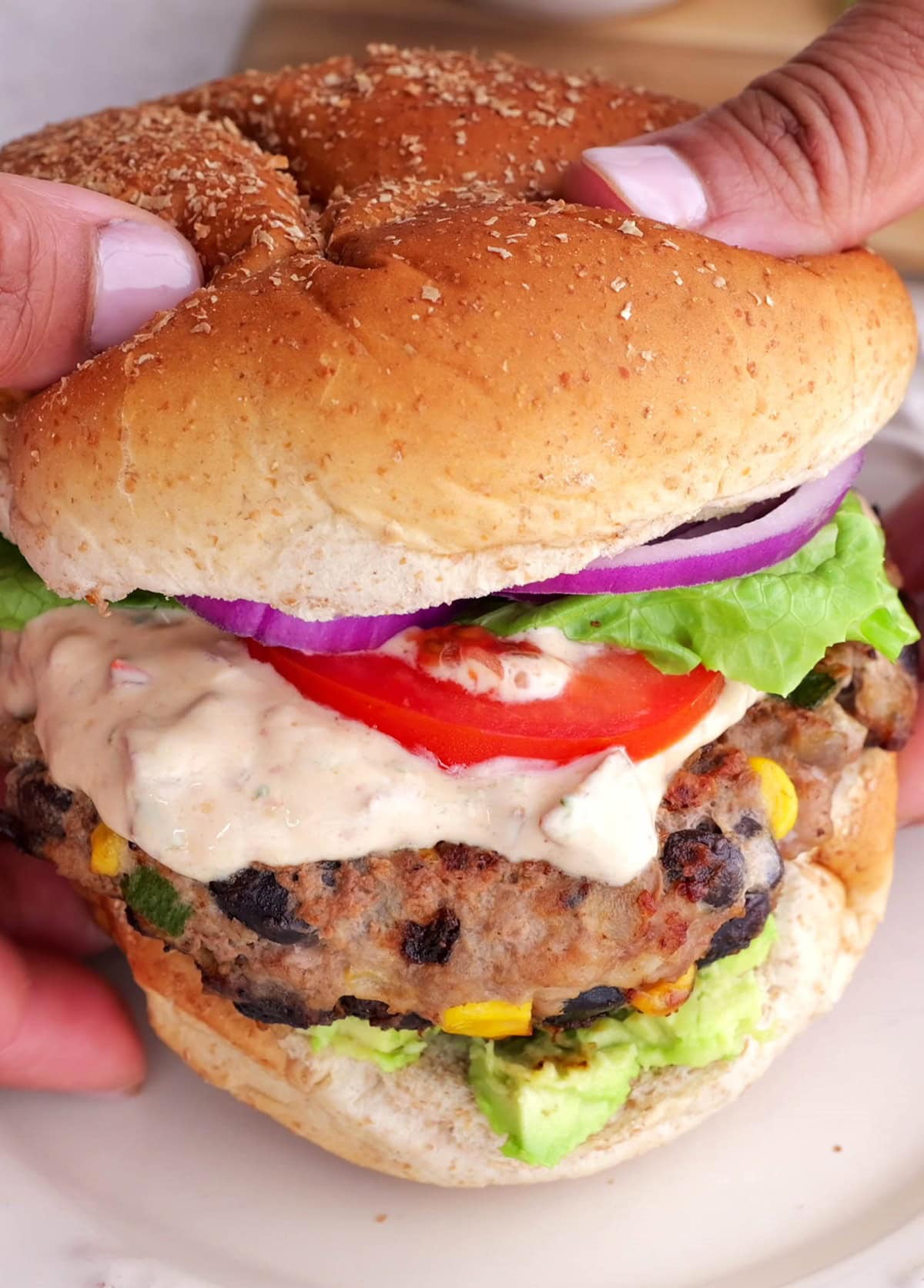 Hands holding a southwest turkey burger, ready to eat.