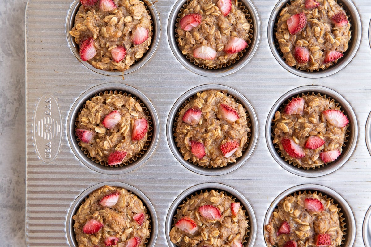 Muffin tin with strawberry banana oatmeal muffins fresh out of the oven.