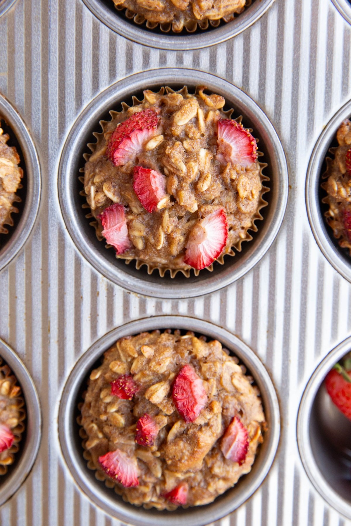Strawberry oat muffins in a muffin tin, fresh out of the oven and ready to eat.