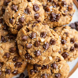 Plate full of vegan peanut butter oatmeal chocolate chip cookies sprinkled with sea salt, ready to eat.