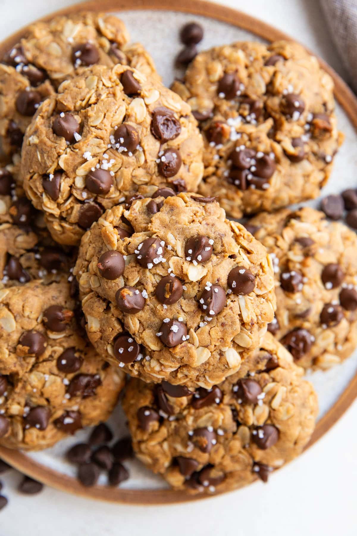 Plate full of vegan peanut butter oatmeal chocolate chip cookies sprinkled with sea salt, ready to eat.