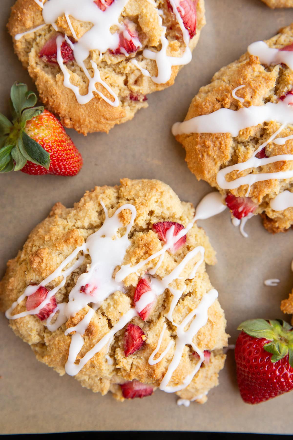 Almond flour scones on a baking sheet drizzled with glaze.