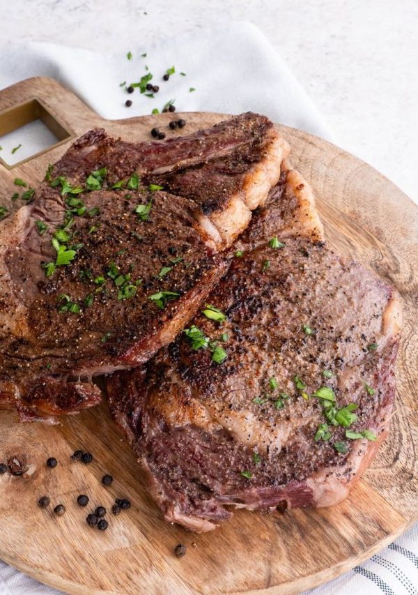 Cutting board of seared ribeye steaks, ready to serve.