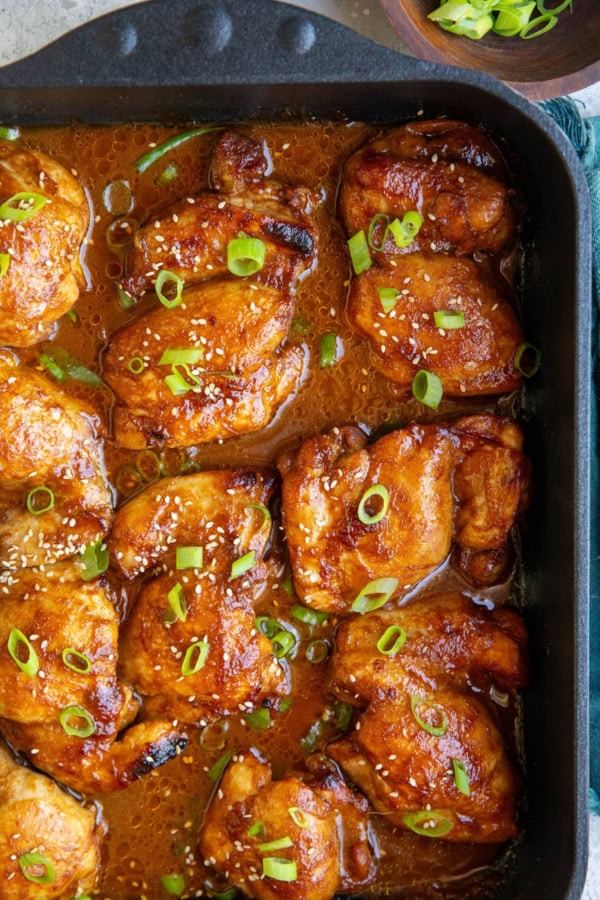 Baking dish full of chicken thighs sitting in marinade, fresh out of the oven.