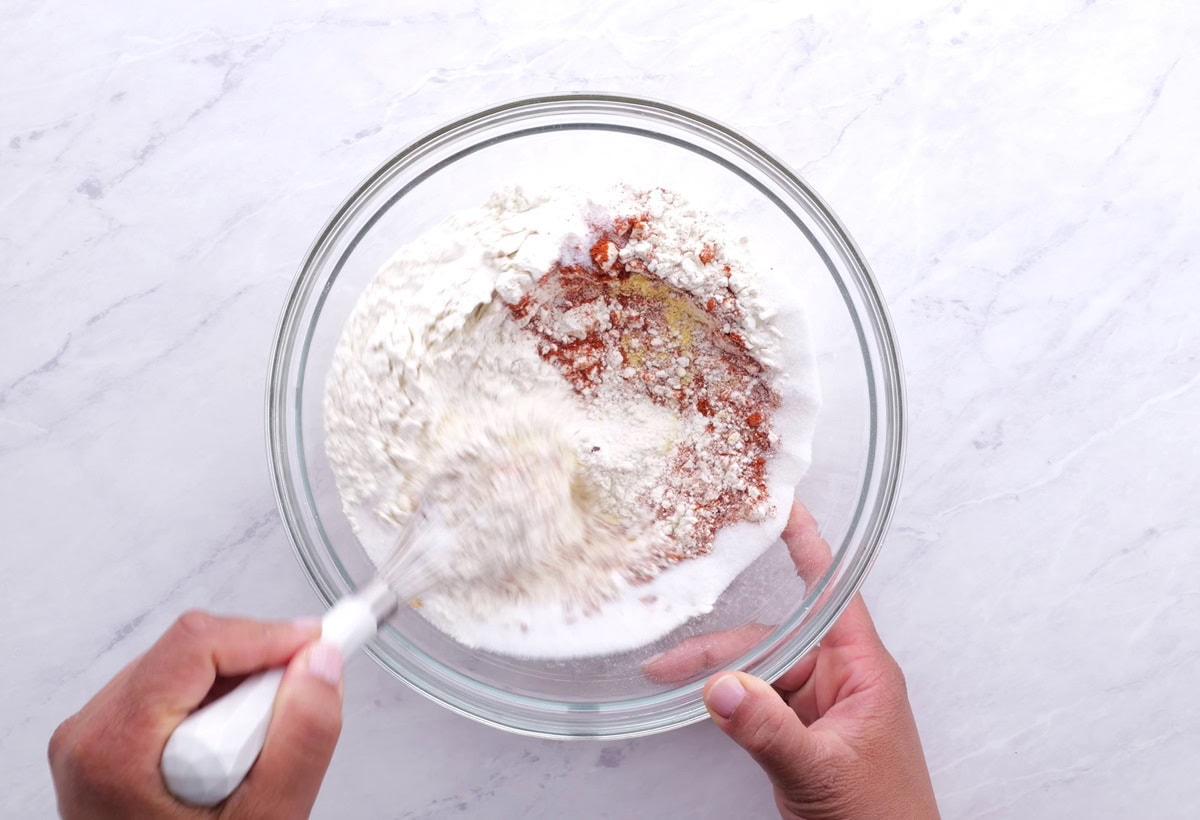 Flour mixture for hush puppies being stirred together in a mixing bowl.