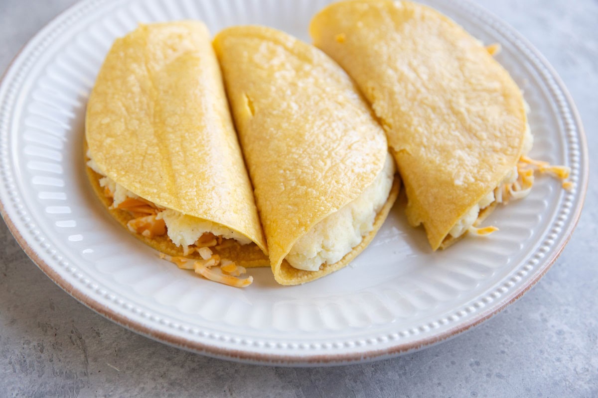 Plate full of potato tacos, ready to be fried.