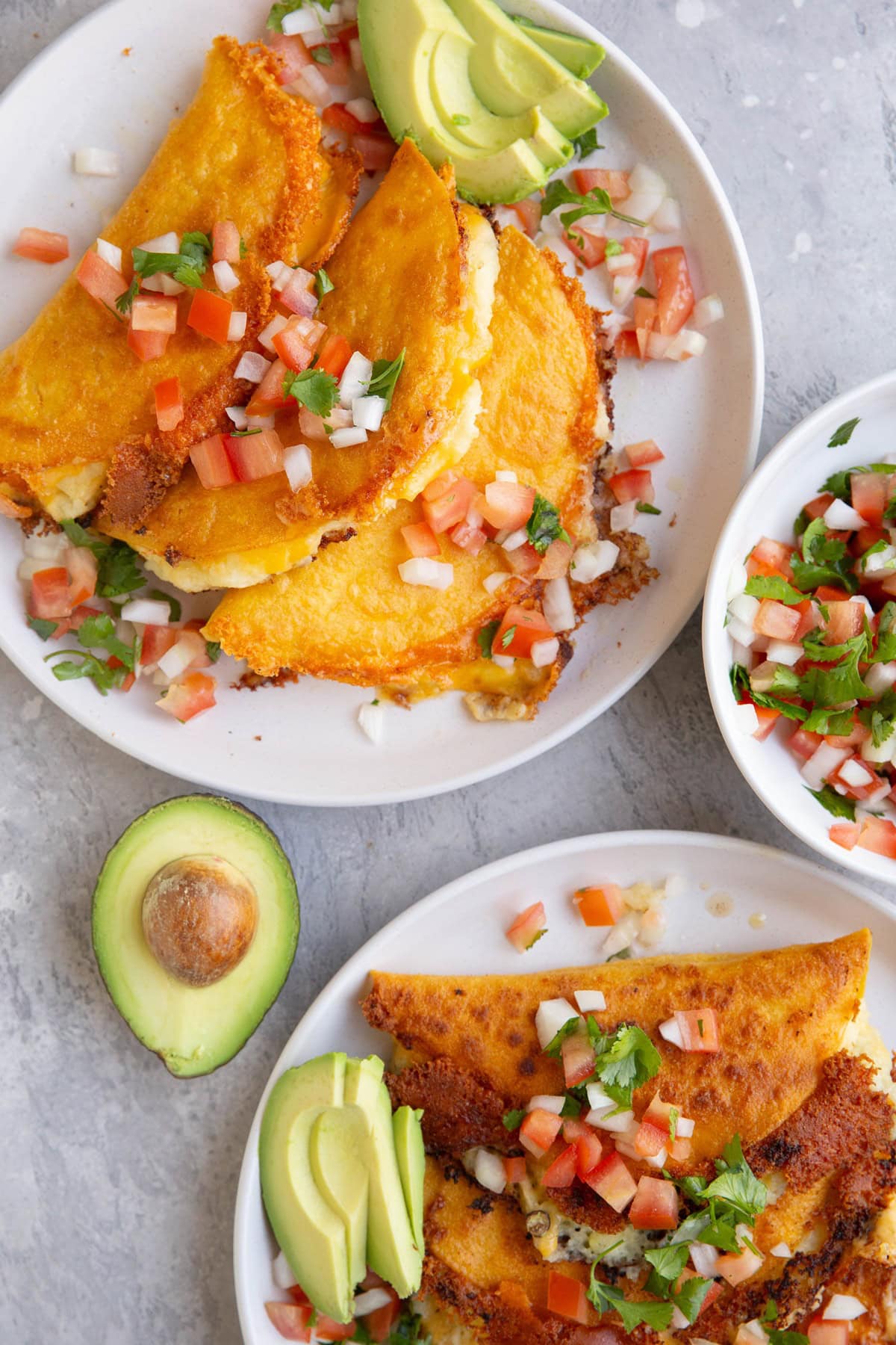 Two plates of potato tacos with pico de gallo on top