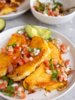 White plate of potato tacos with a bowl of pico de gallo in the background.