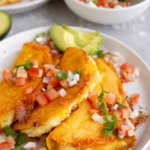 White plate of potato tacos with a bowl of pico de gallo in the background.