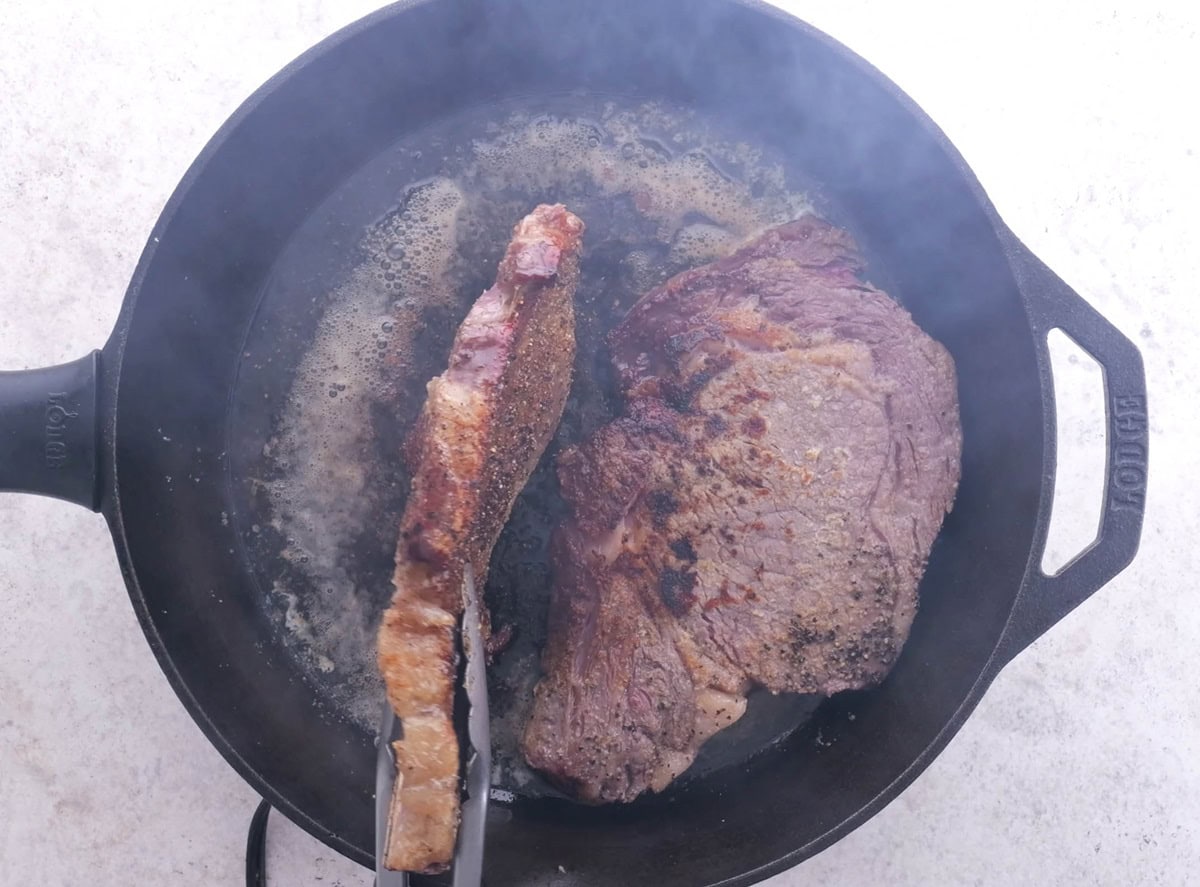 Searing the edges of the steaks.