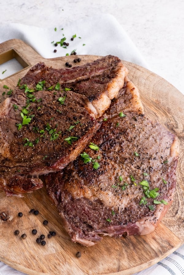 Cutting board of seared ribeye steaks, ready to serve.