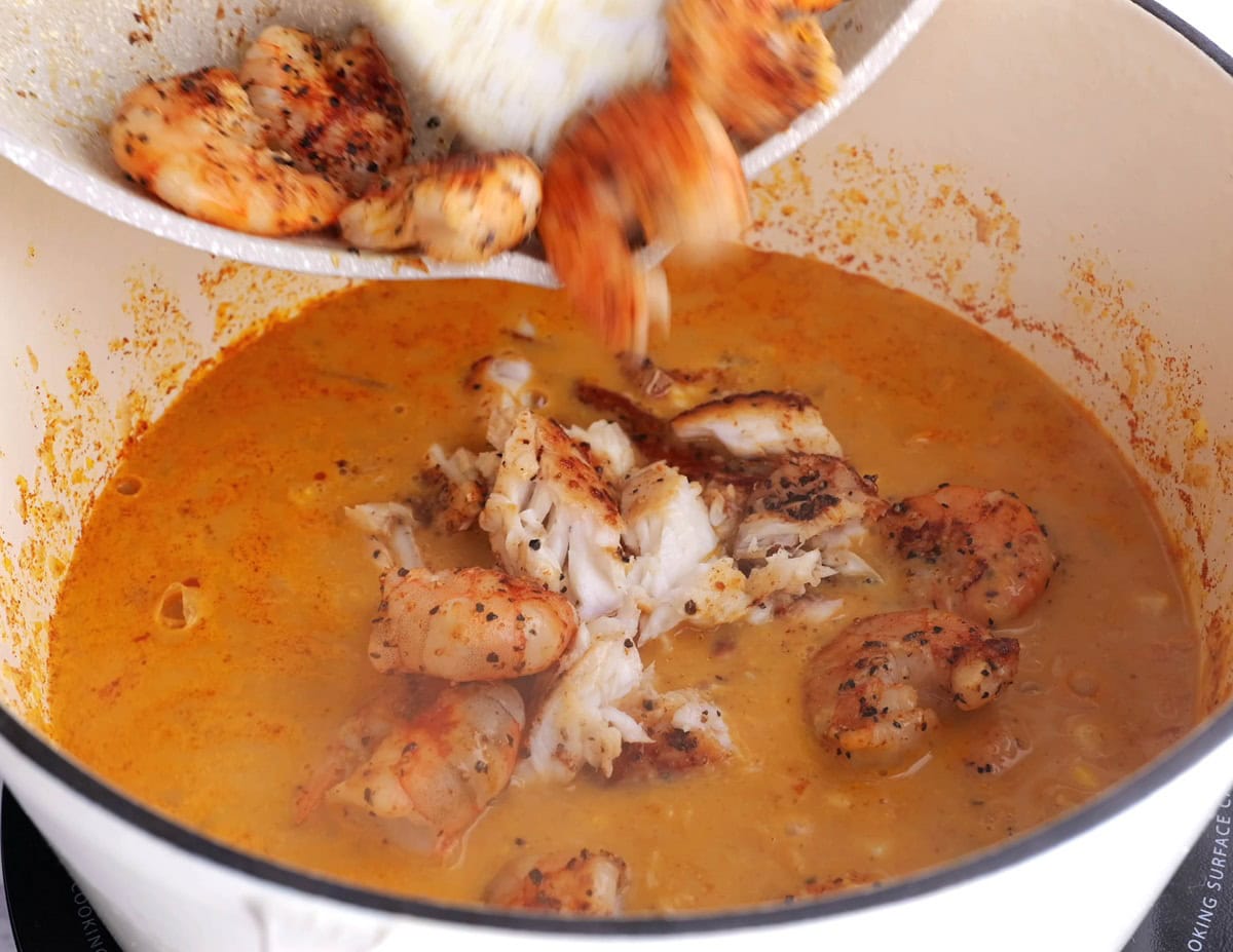 Corn chowder in a pot with sole and shrimp.