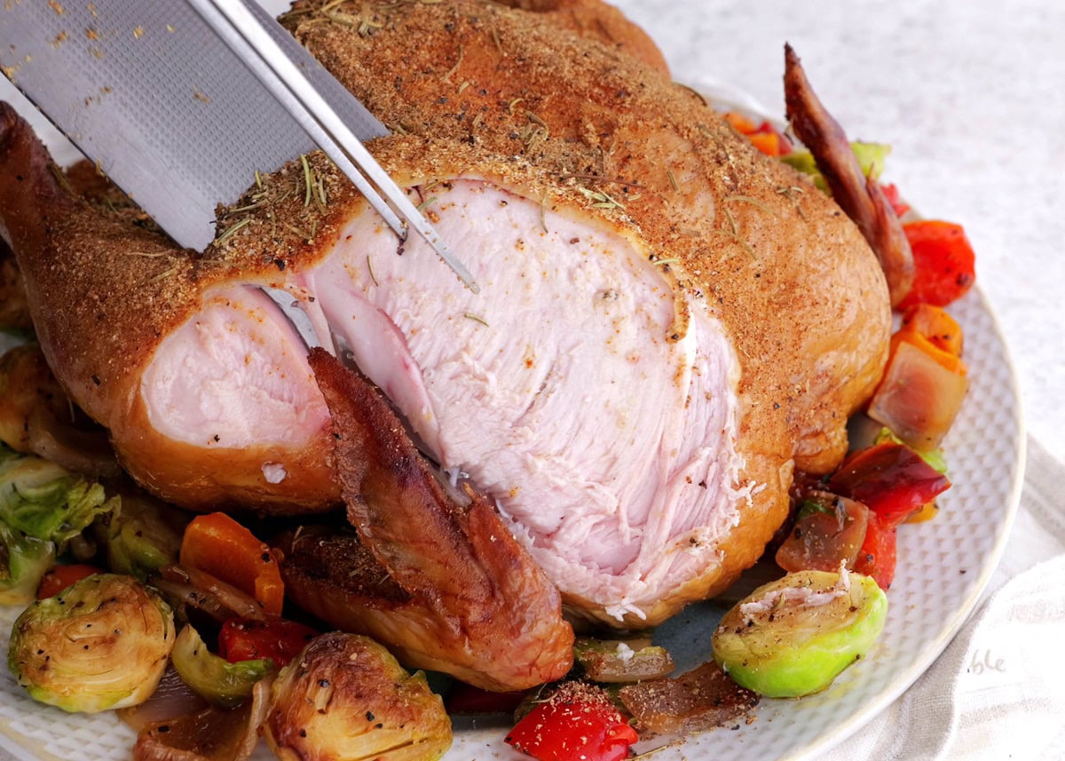 Knife cutting chicken into slices.