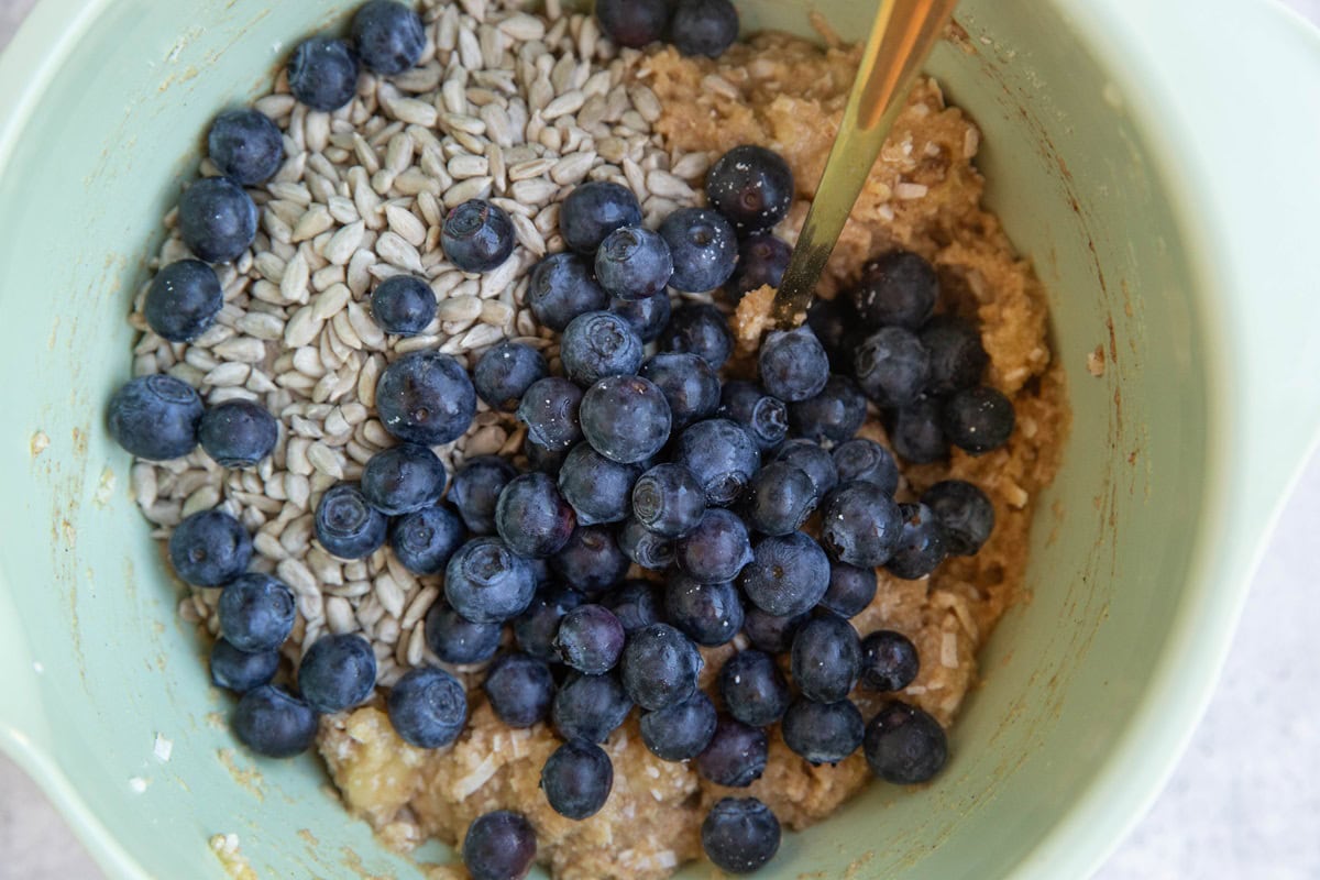 sunflower seeds and blueberries on top of breakfast bar batter ready to be mixed in.