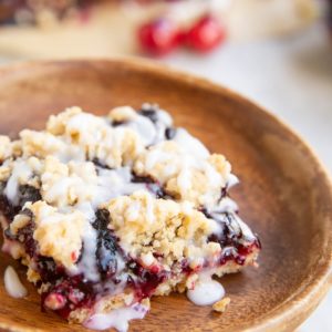 Slice of cherry pie bar on a wooden plate, ready to serve.