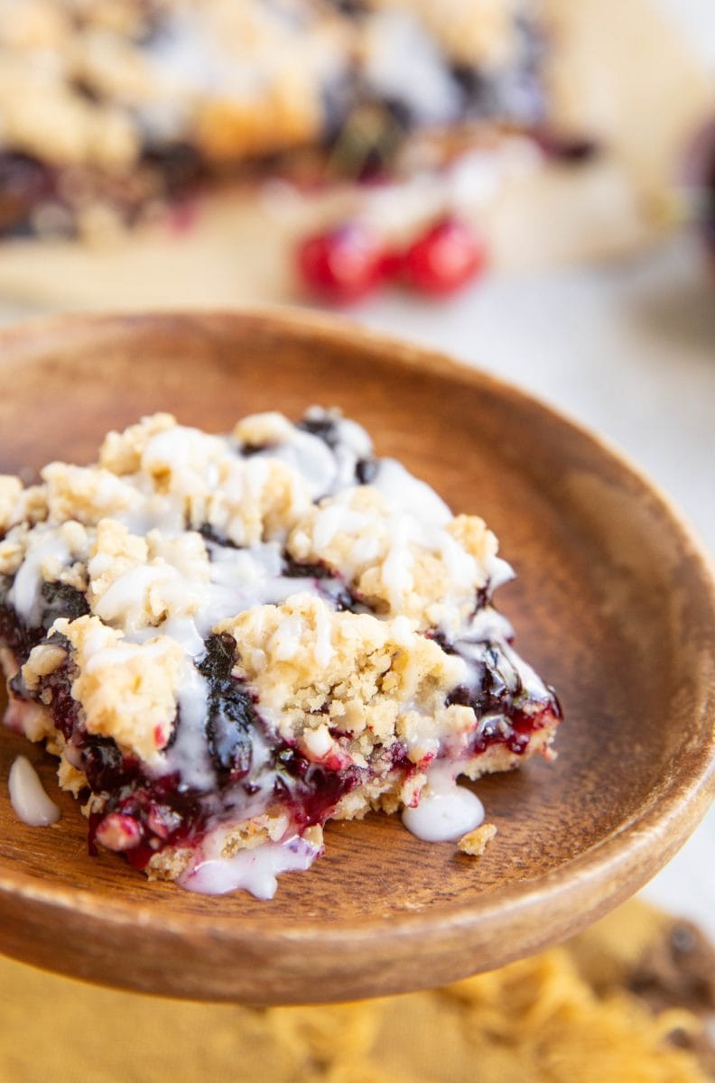 Slice of cherry pie bar on a wooden plate, ready to serve.