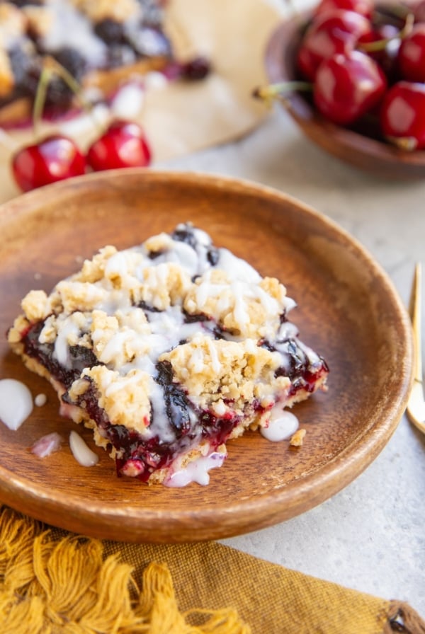 Slice of cherry bar on a wooden plate with the rest of the bars in the background.