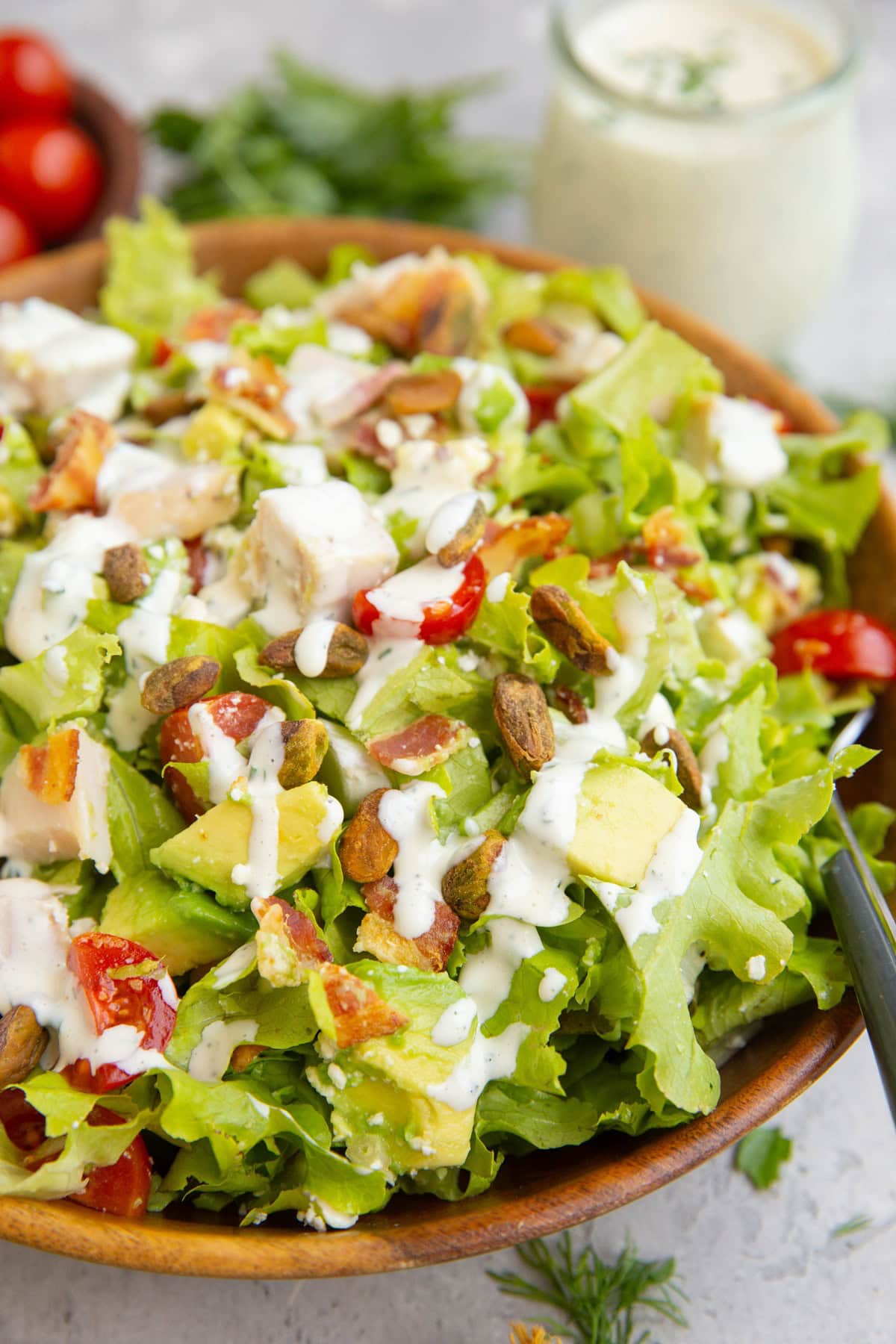 Bowl of chicken bacon avocado salad drizzled with ranch dressing.