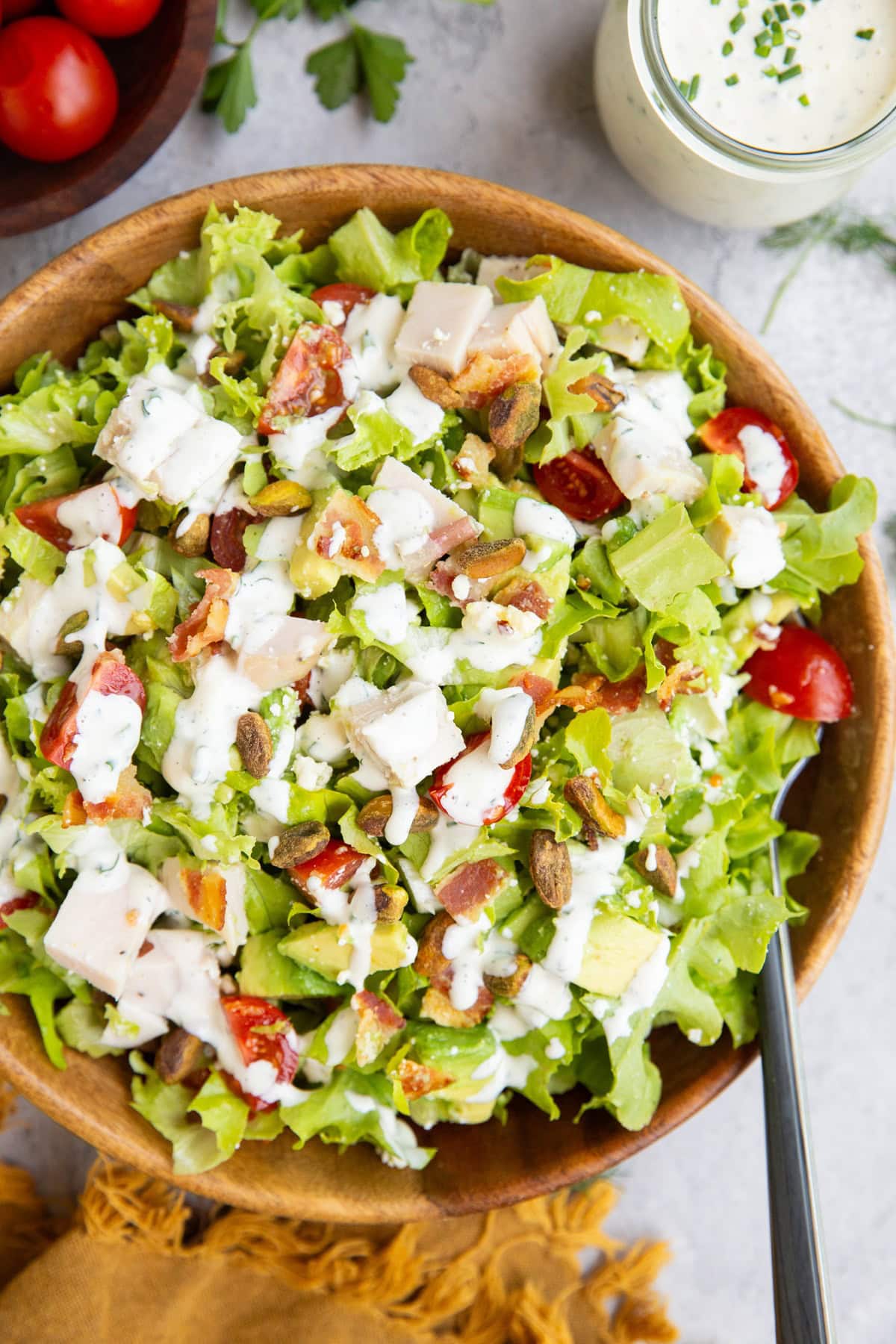 Wooden bowl of salad ingredients, drizzled with dressing.