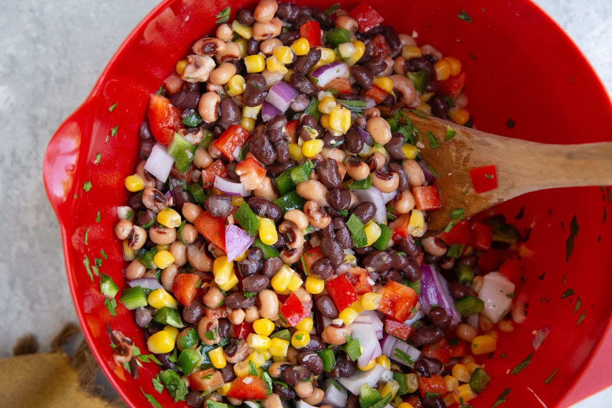 Mixing bowl with Texas caviar all mixed up with a wooden spoon, ready to serve.
