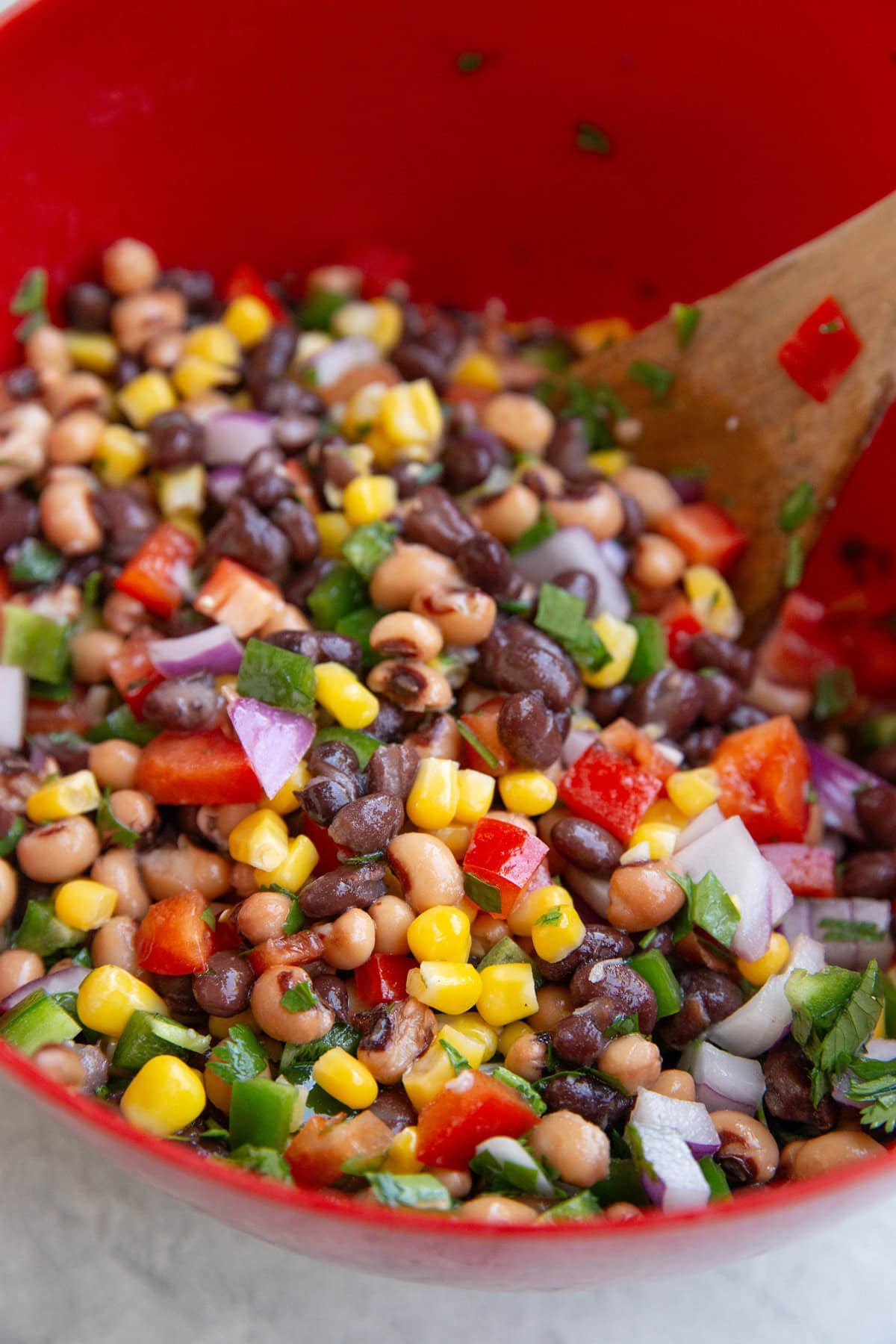 Cowboy caviar in a large mixing bowl with a wooden spoon, ready to serve.