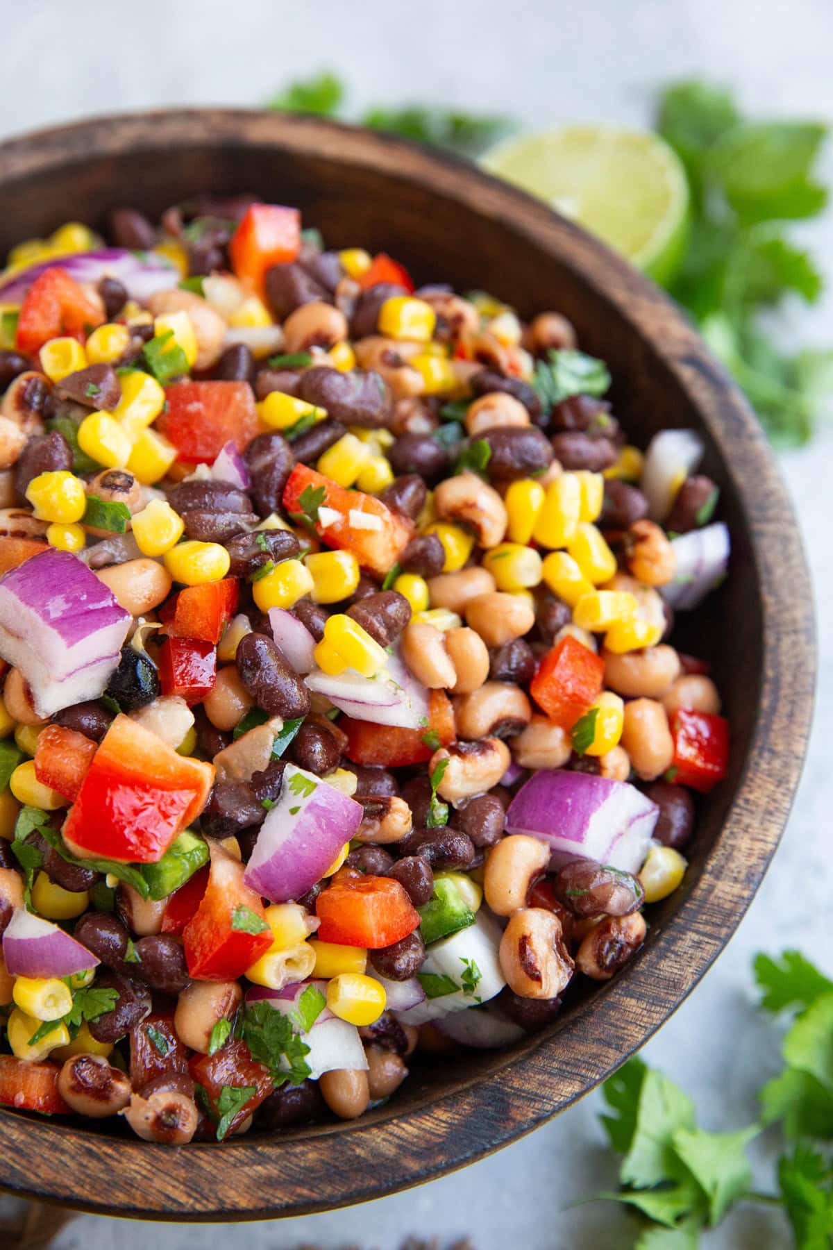 Wooden bowl full of Cowboy Caviar, ready to serve with chips as an appetizer.