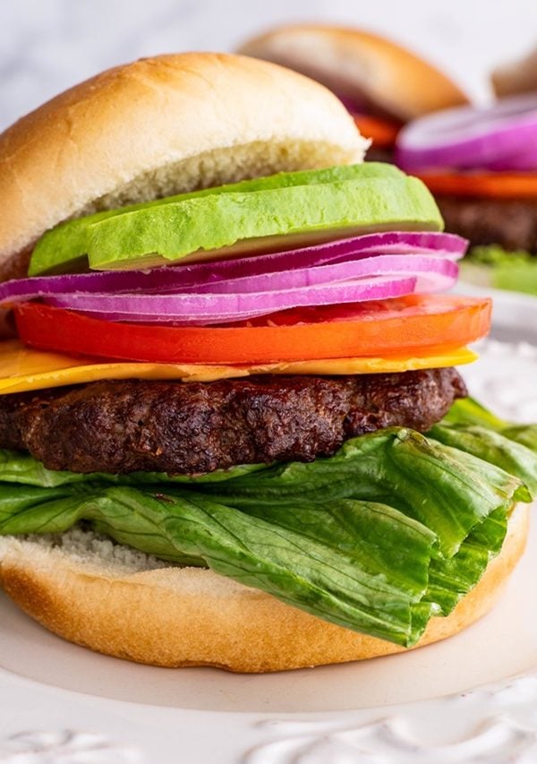 Cheeseburger on a plate with toppings and a bun. Ready to consume.
