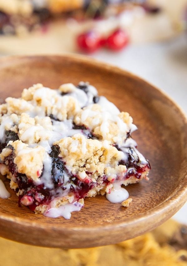 Slice of cherry pie bar on a wooden plate.