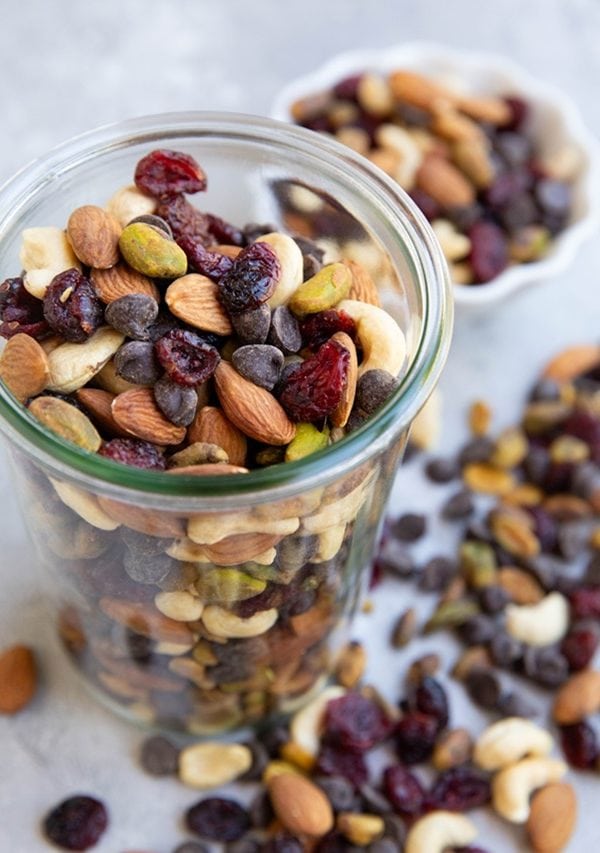 Jar of trail mix with a bunch of trailmix spilled over the side.