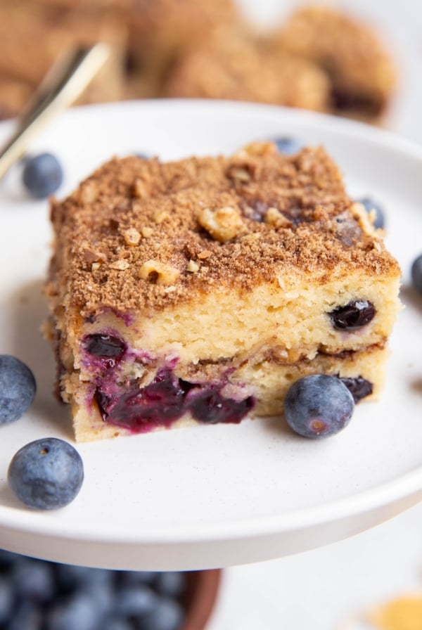Close up slice of yogurt coffee cake on a plate with fresh berries, ready to serve.