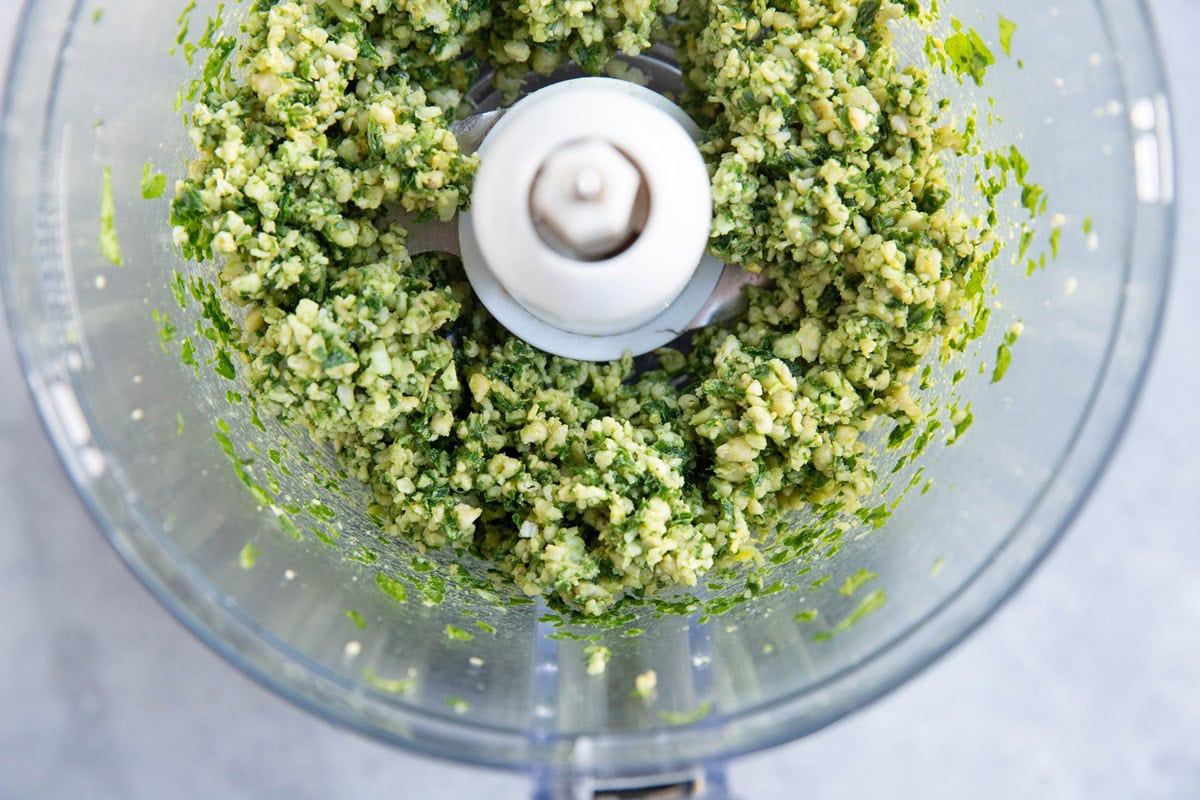 Pesto sauce ingredients pulsed into small chunks in a food processor.