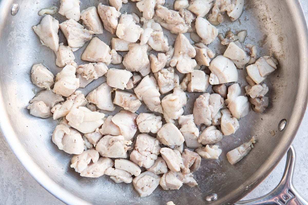 Skillet with pieces of cooked chicken inside.