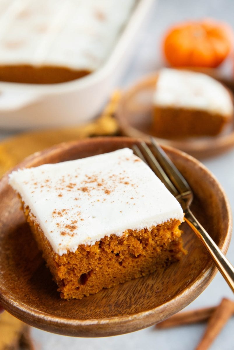 Two plates of slices of pumpkin cake frosted with cream cheese frosting, ready to eat.