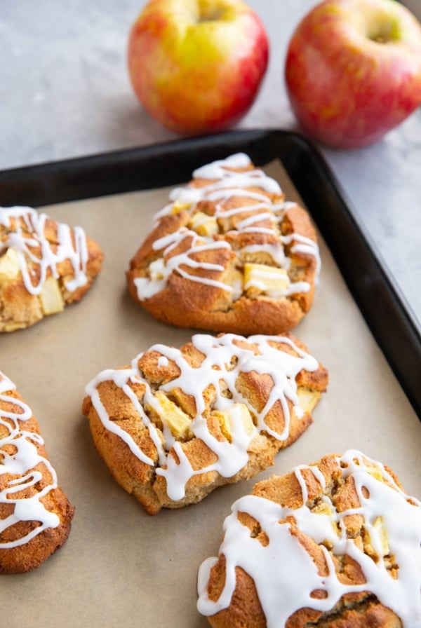 Baking sheet of almond flour apple scones with fresh apples in the background.