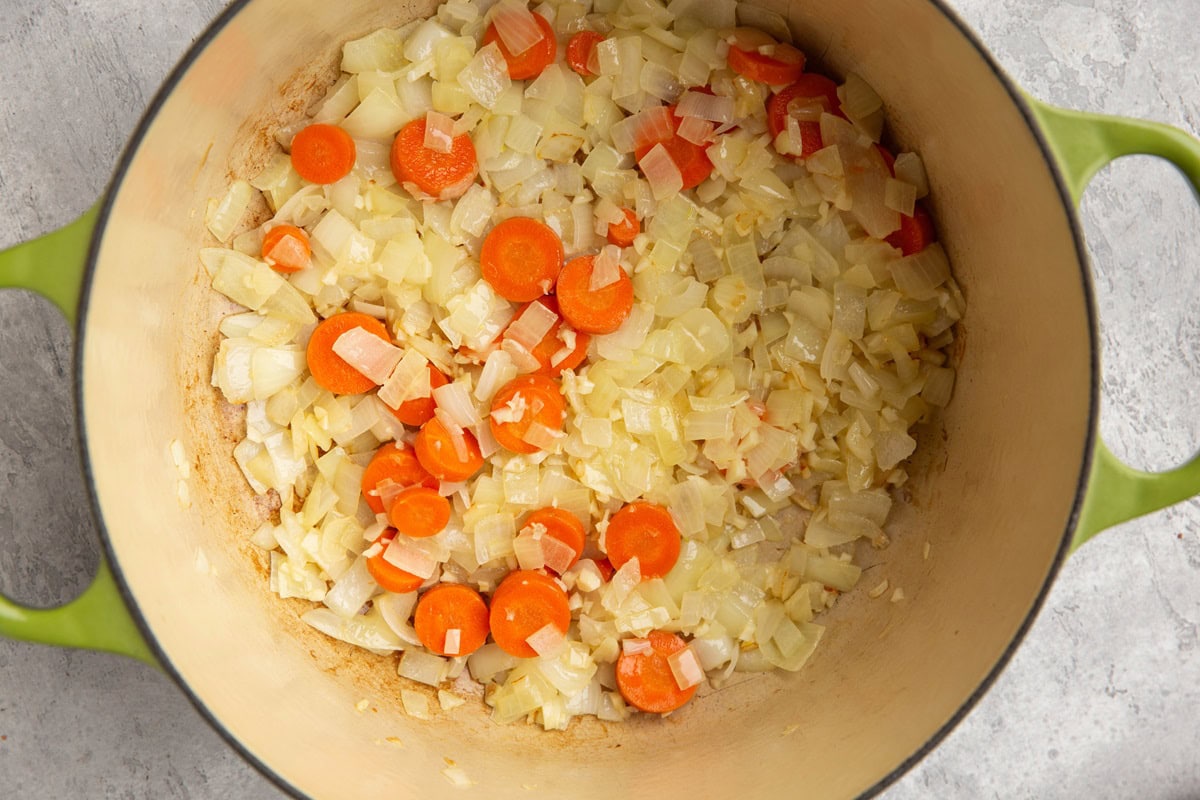 Large pot with onion, garlic, and carrots cooking.