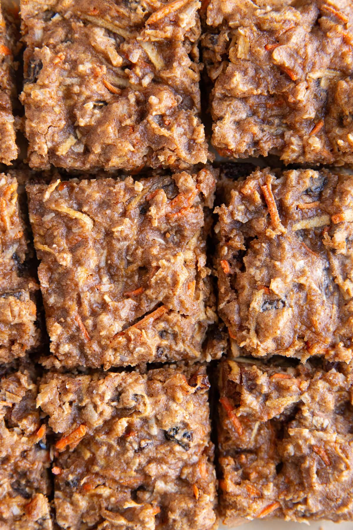 Sliced carrot cake bars on a sheet of parchment paper.