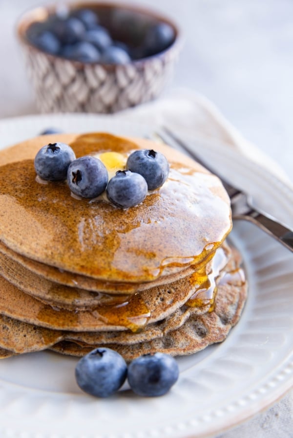Stack of buckwheat pancakes with blueberries on top.