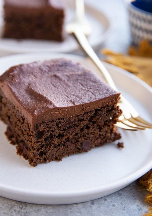Two slices of black bean chocolate cake on white plates with golden forks, ready to serve.