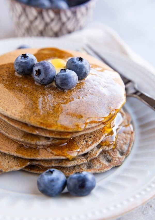 Stack of buckwheat pancakes with blueberries on top.