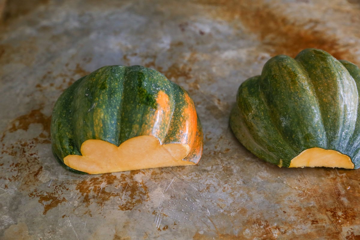 Acorn squash halves on a baking sheet cut side down. Ready to go into the oven to roast.