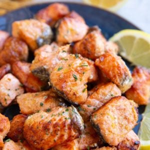 Blue plate with a pile of salmon bites on top, ready to be eaten.