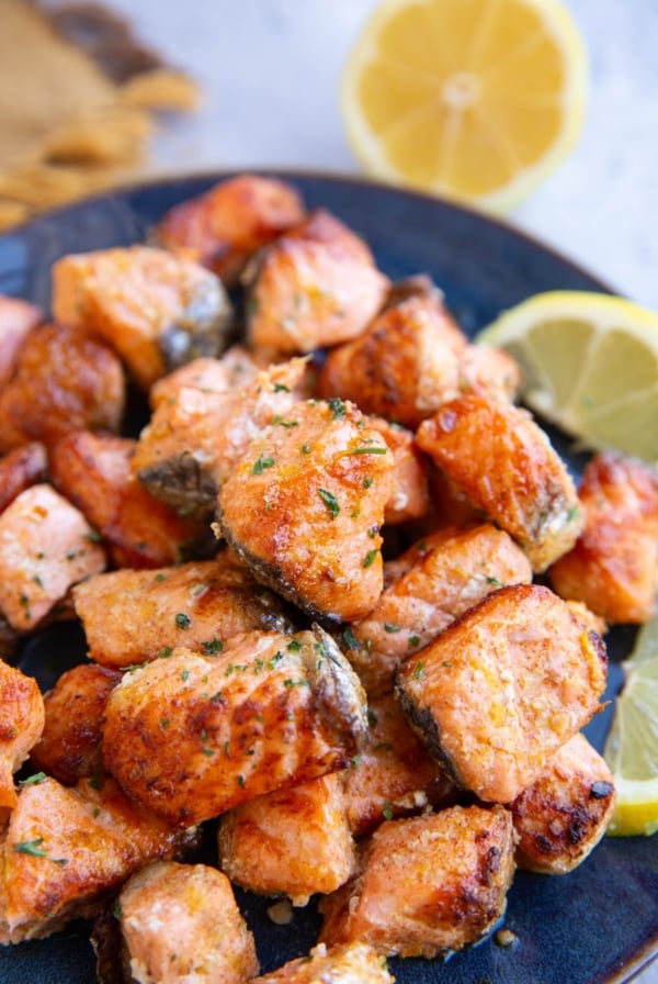 Blue plate with a pile of salmon bites on top, ready to be eaten.