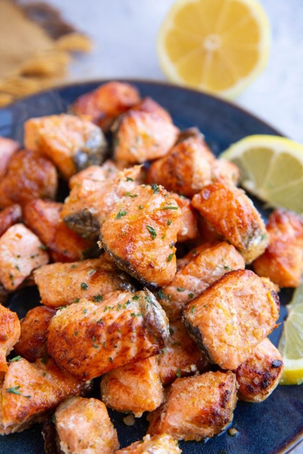 Blue plate with a pile of salmon bites on top, ready to be eaten.