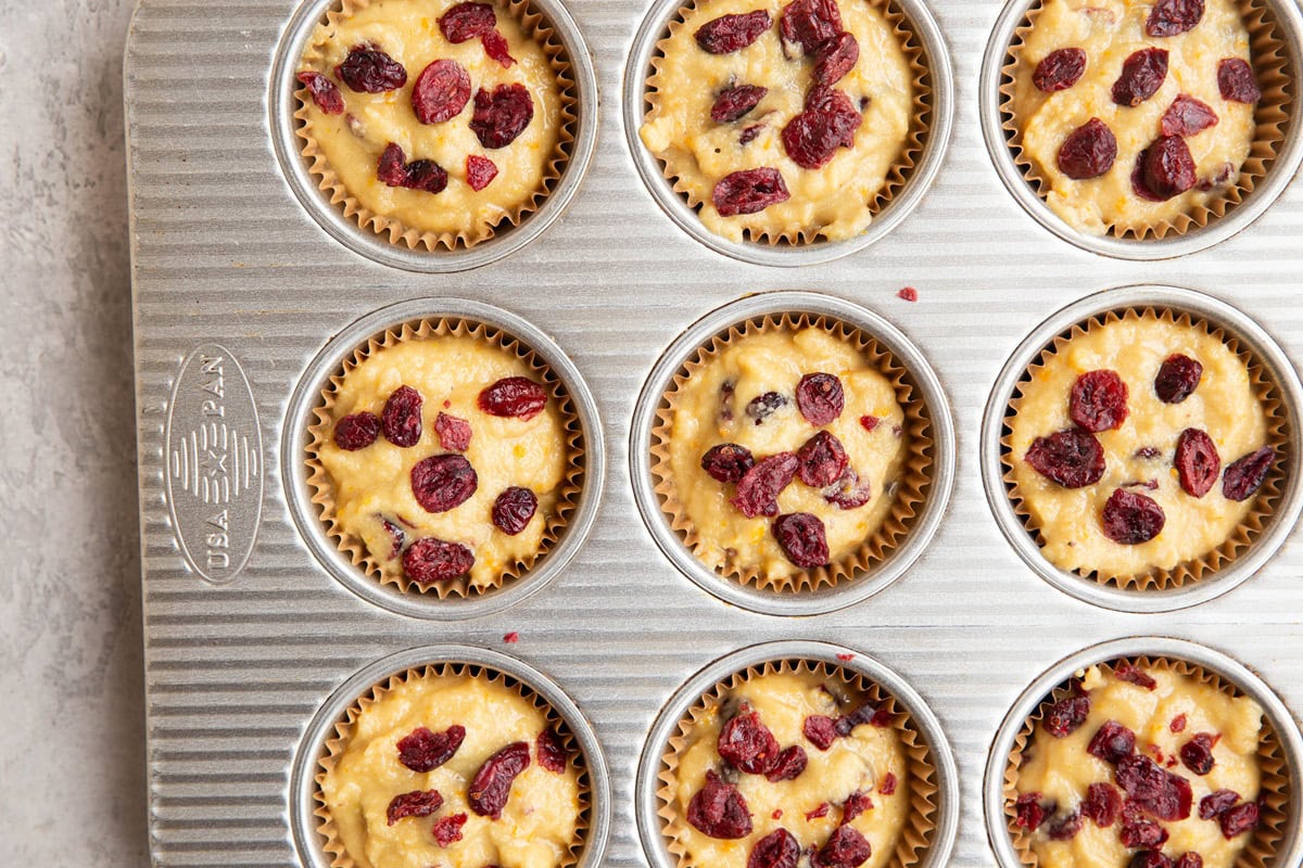 Muffin tin full of cranberry orange muffin batter.