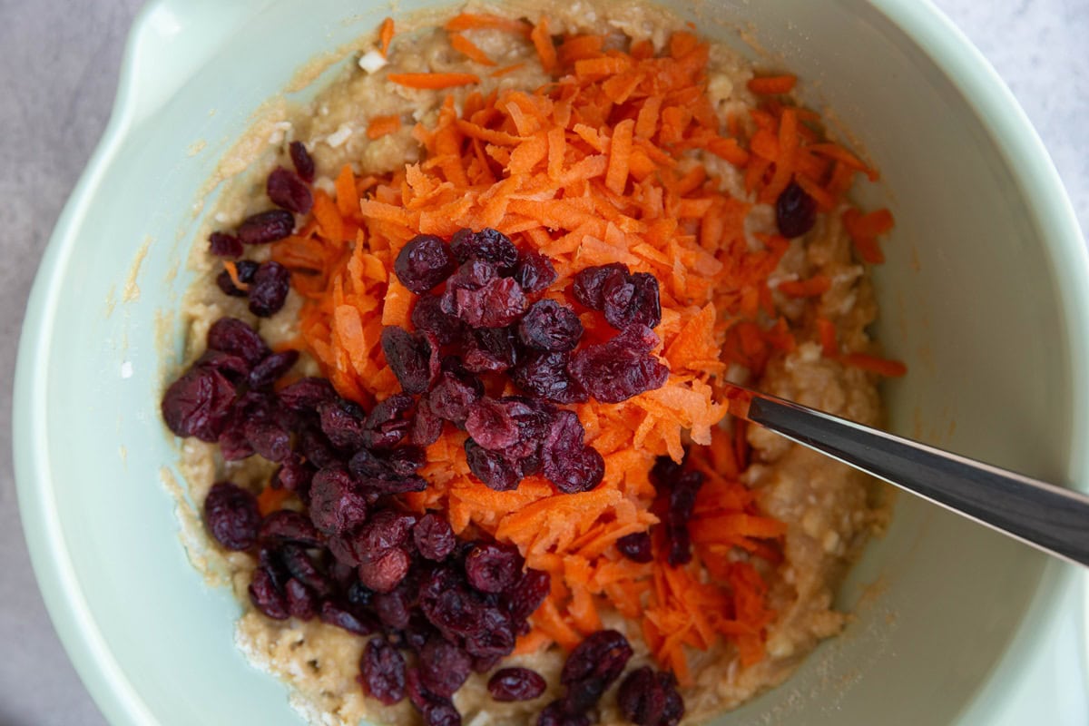 Grated carrots and dried cranberries in a mixing bowl.