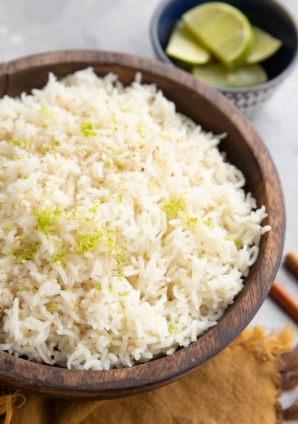 Big wooden bowl full of white rice with lime zest on top.