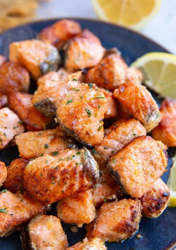 Blue plate with a pile of salmon bites on top, ready to be eaten.