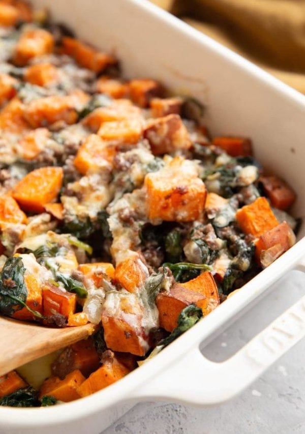 Sweet potato, ground beef, and spinach in a casserole dish.