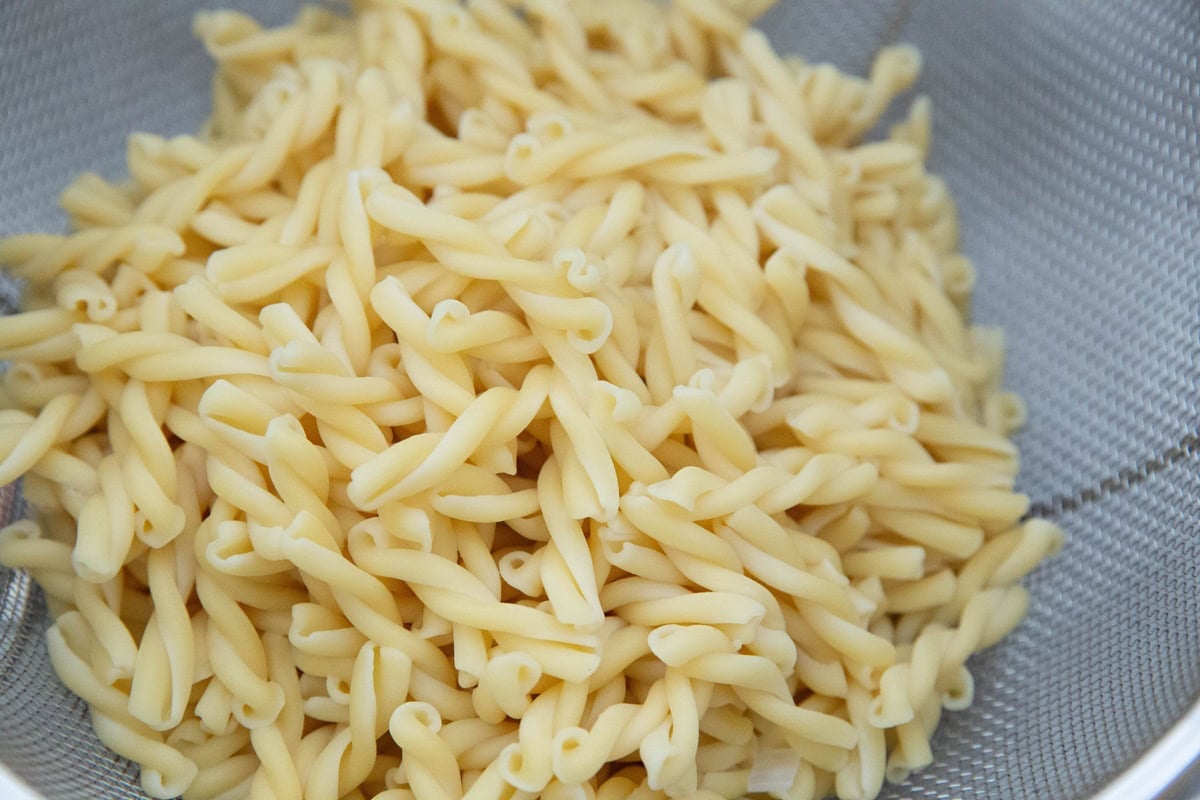 Colander full of cooked pasta noodles.