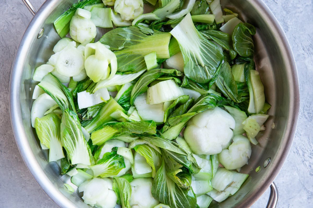Skillet full of chopped bok choy, sautéing for stir fry.
